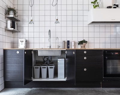 Minimalist modern apartment kitchen featuring charcoal black cabinetry and subtle gold accents.