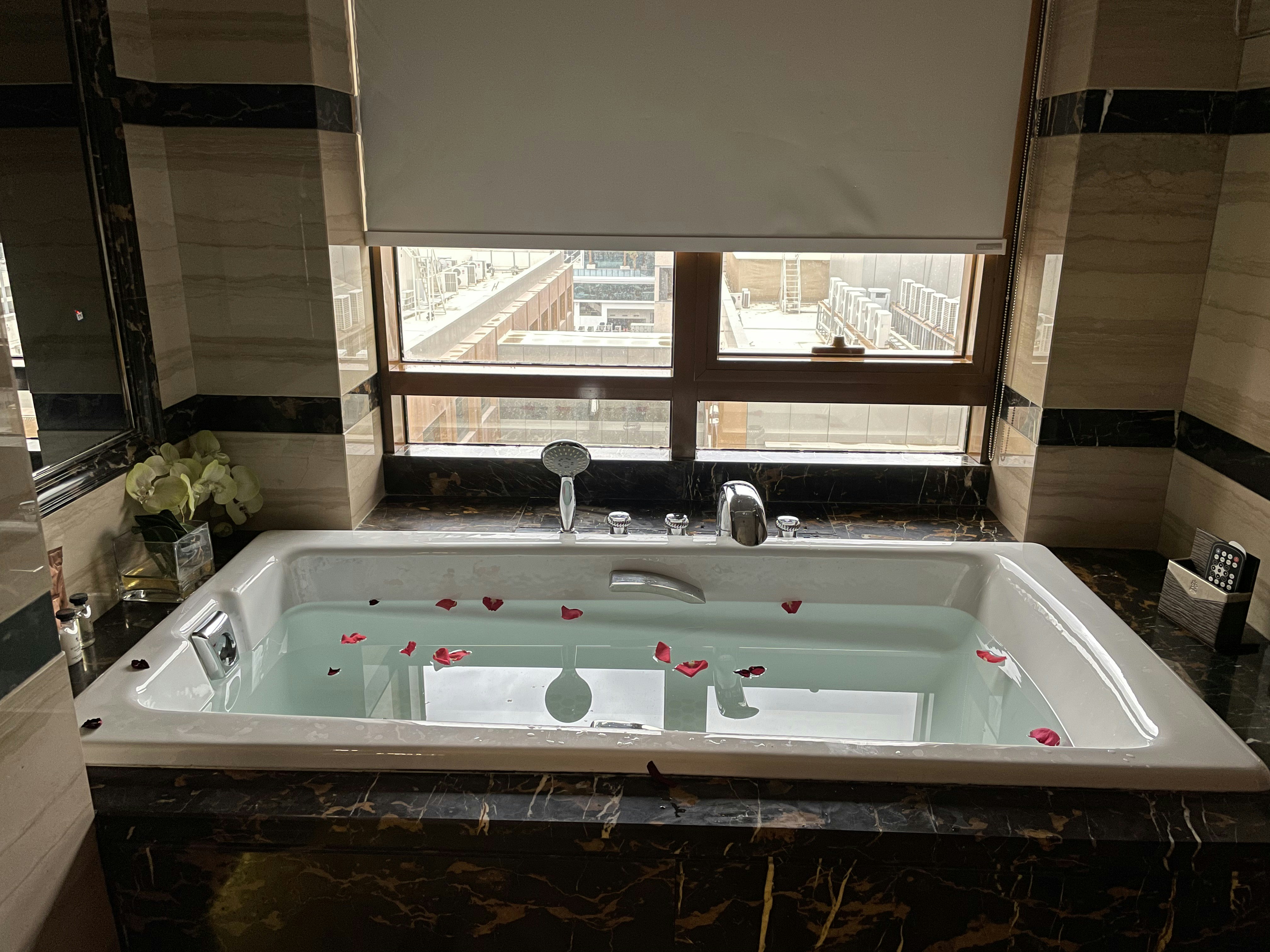 Warm spa bath with rose petals, candles, and steam rising over a luxury bathtub