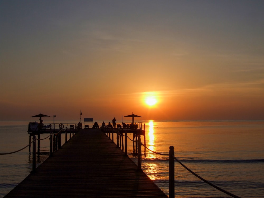 brown wooden dock on sea during sunset