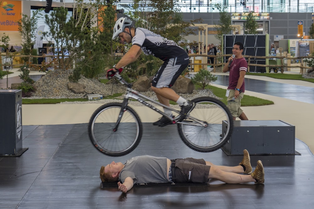 man in black t-shirt and black shorts riding on black and white bicycle during daytime