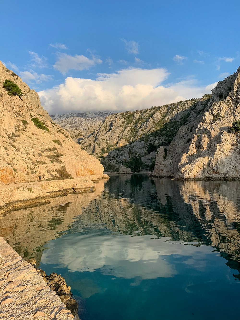 body of water between mountains under blue sky during daytime