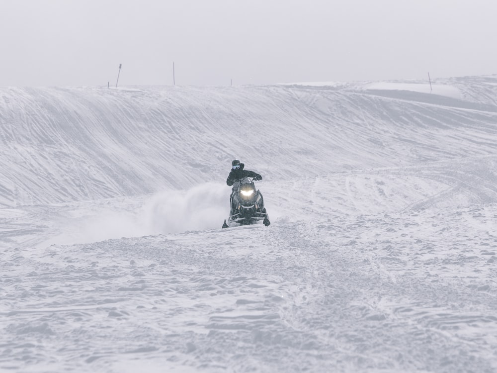 person riding on black motorcycle on snow covered field during daytime
