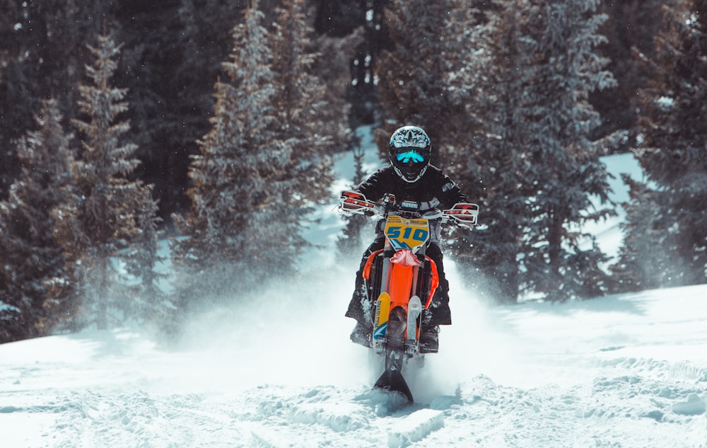 person riding orange and black snow mobile