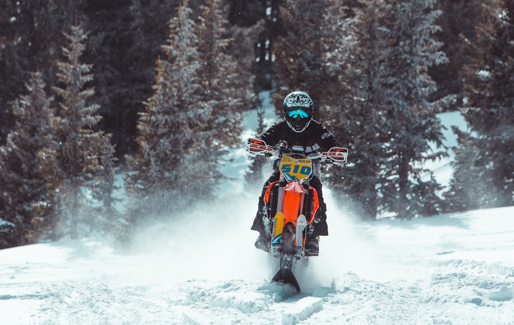 Persona montada en moto de nieve naranja y negra