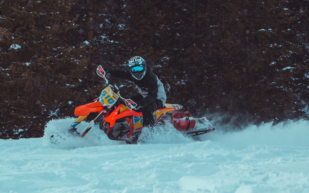 person riding orange snow mobile