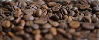 Close-up of glossy coffee beans resting on a sleek black matte surface with golden highlights.