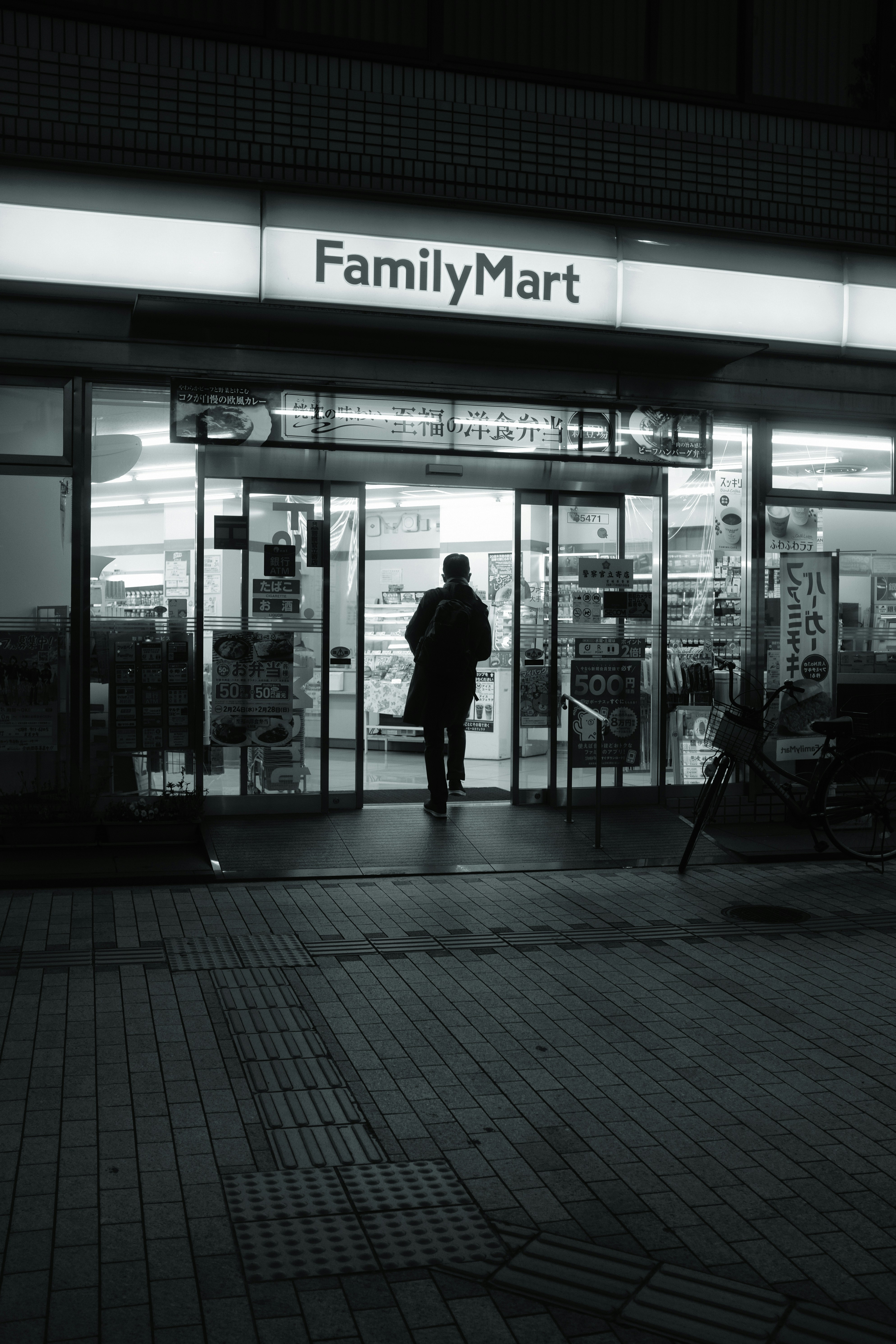grayscale photo of man standing in front of glass door