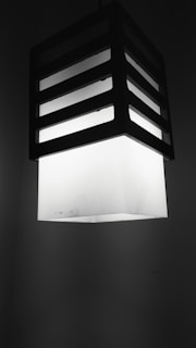 A sleek, minimalist black and white photo of a modern lighting fixture casting soft shadows.