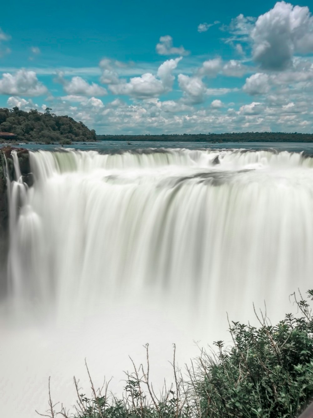water falls under blue sky and white clouds during daytime