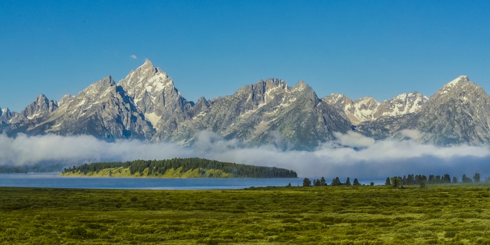 green grass field near snow covered mountain during daytime