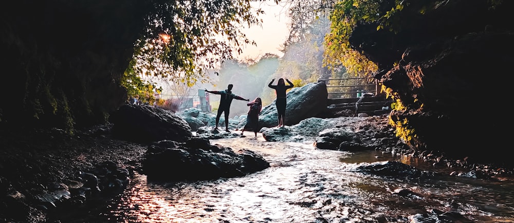 3 women standing on rock near water falls during daytime