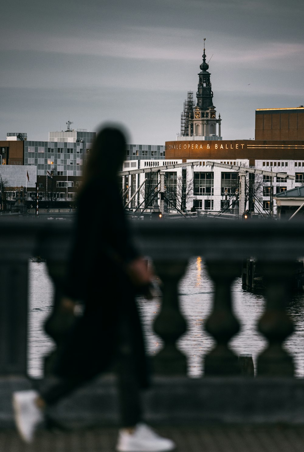 woman in black coat standing near body of water during daytime