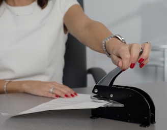 woman in white shirt holding pen writing on white paper