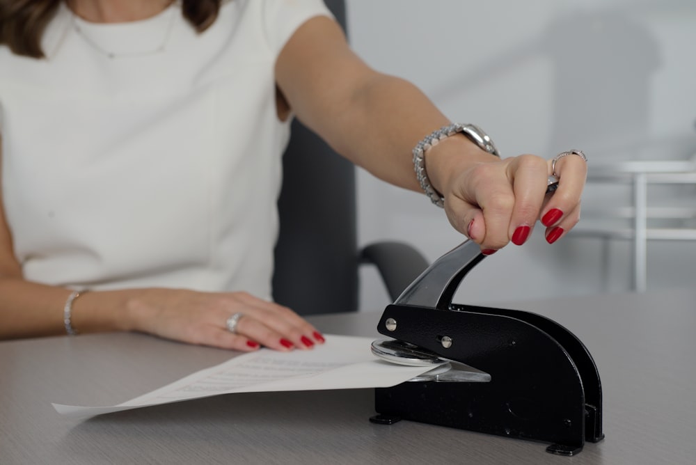 woman in white shirt holding pen writing on white paper