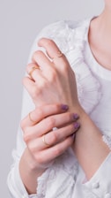a woman in a white shirt is holding her hands together