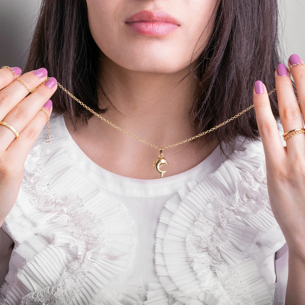 a woman wearing a gold necklace with a crescent charm