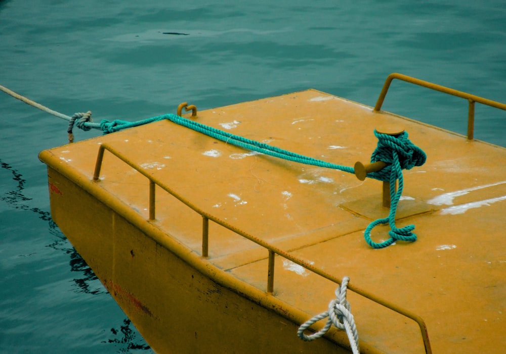 a yellow boat tied to a rope in the water