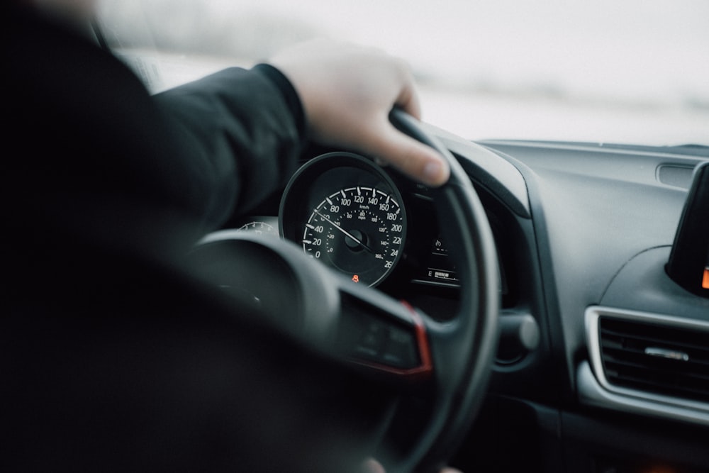 persona in camicia nera a maniche lunghe che guida l'auto