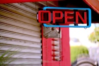 a red and blue open sign hanging from the side of a building