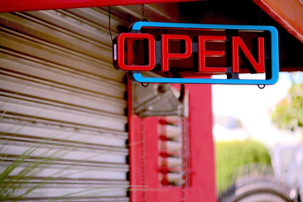 a red and blue open sign hanging from the side of a building