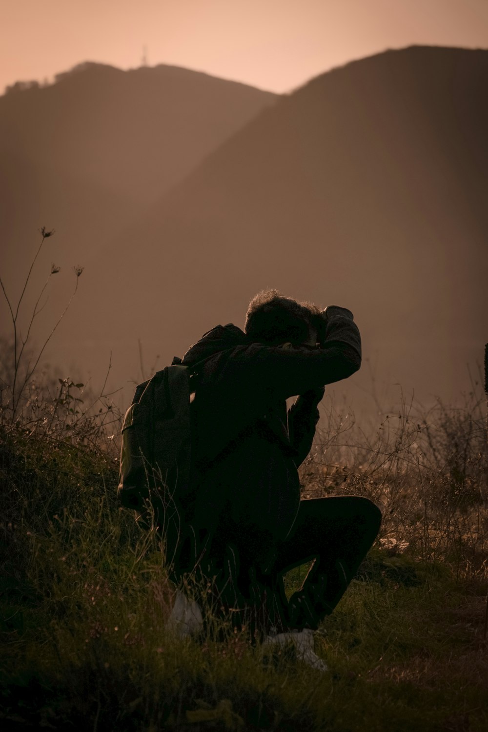 Mann in schwarzer Jacke und Hose sitzt auf Felsen