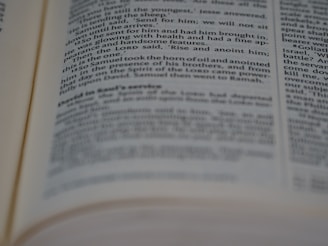 A close-up view of an open book showing printed text in English. The text is in two columns, with portions of it slightly out of focus due to the depth of field.