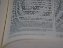 A close-up view of an open book showing printed text in English. The text is in two columns, with portions of it slightly out of focus due to the depth of field.