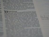 The image contains a close-up of a page from a book, displaying text from the Bible with verses and references. The section visible includes the story of David and Goliath. The text is printed in a serif font in black ink on a white page. Some portions of the page are visible, with a line of dots and faint handwriting or annotation on the right.