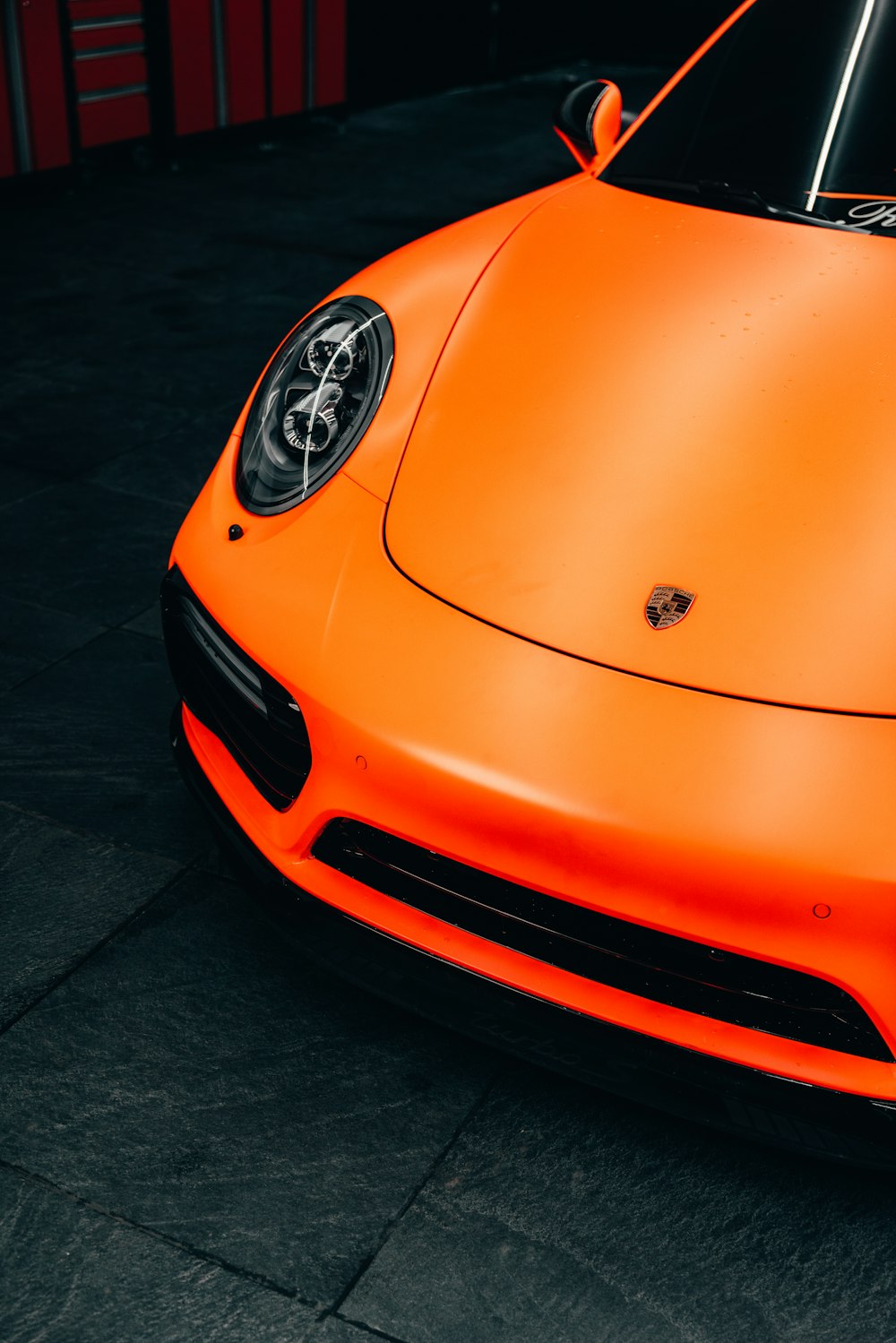 Porsche 911 naranja aparcado sobre pavimento negro