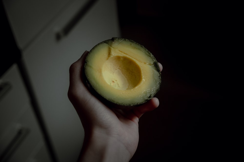 person holding green round fruit