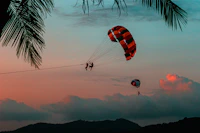 silhouette of 2 person riding parachute during sunset