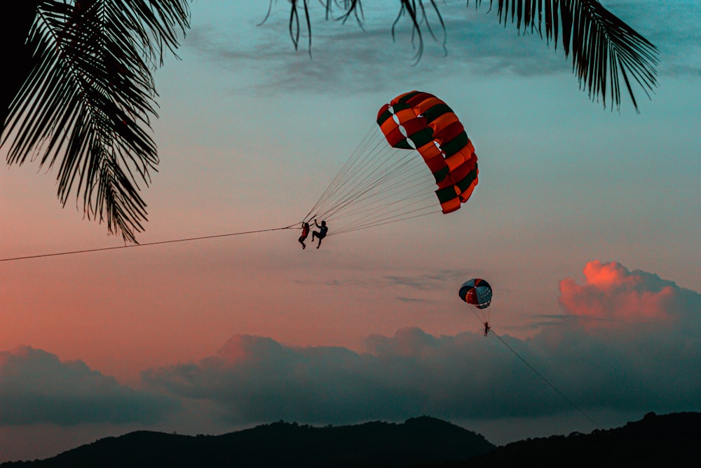 silhouette of 2 person riding parachute during sunset