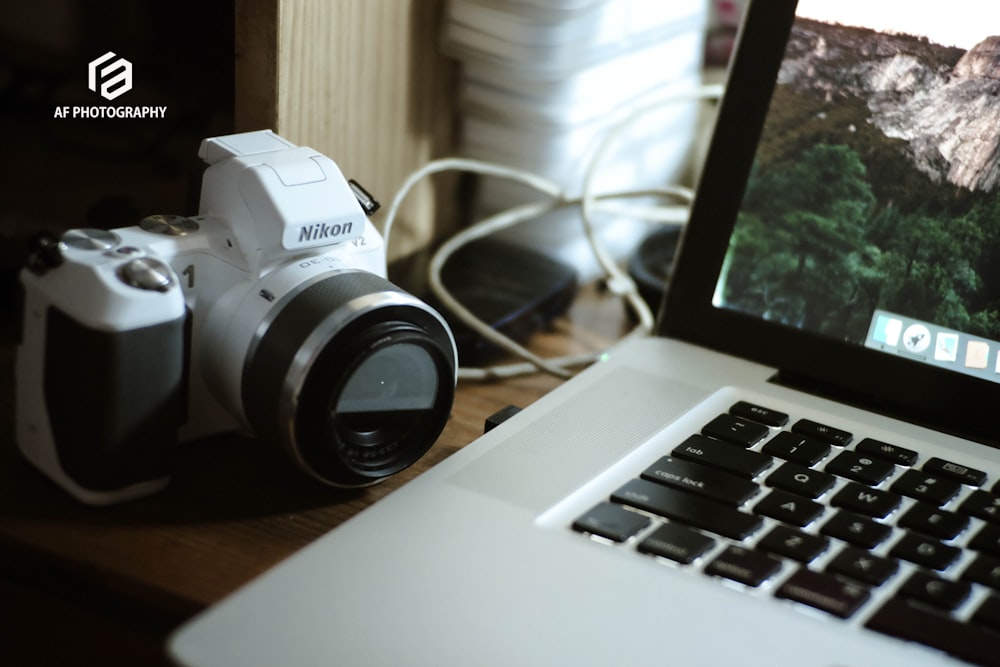 black and silver canon dslr camera beside macbook pro
