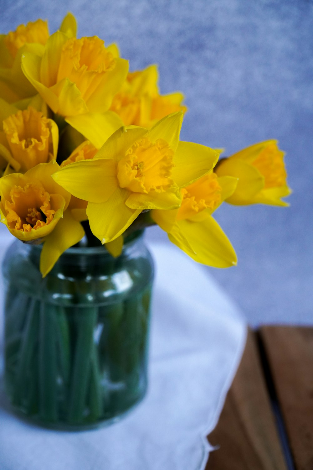 yellow flowers in green glass vase