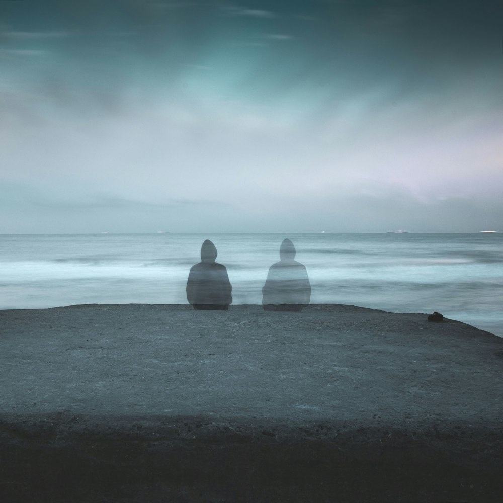 3 white and gray stone on black sand near body of water during daytime