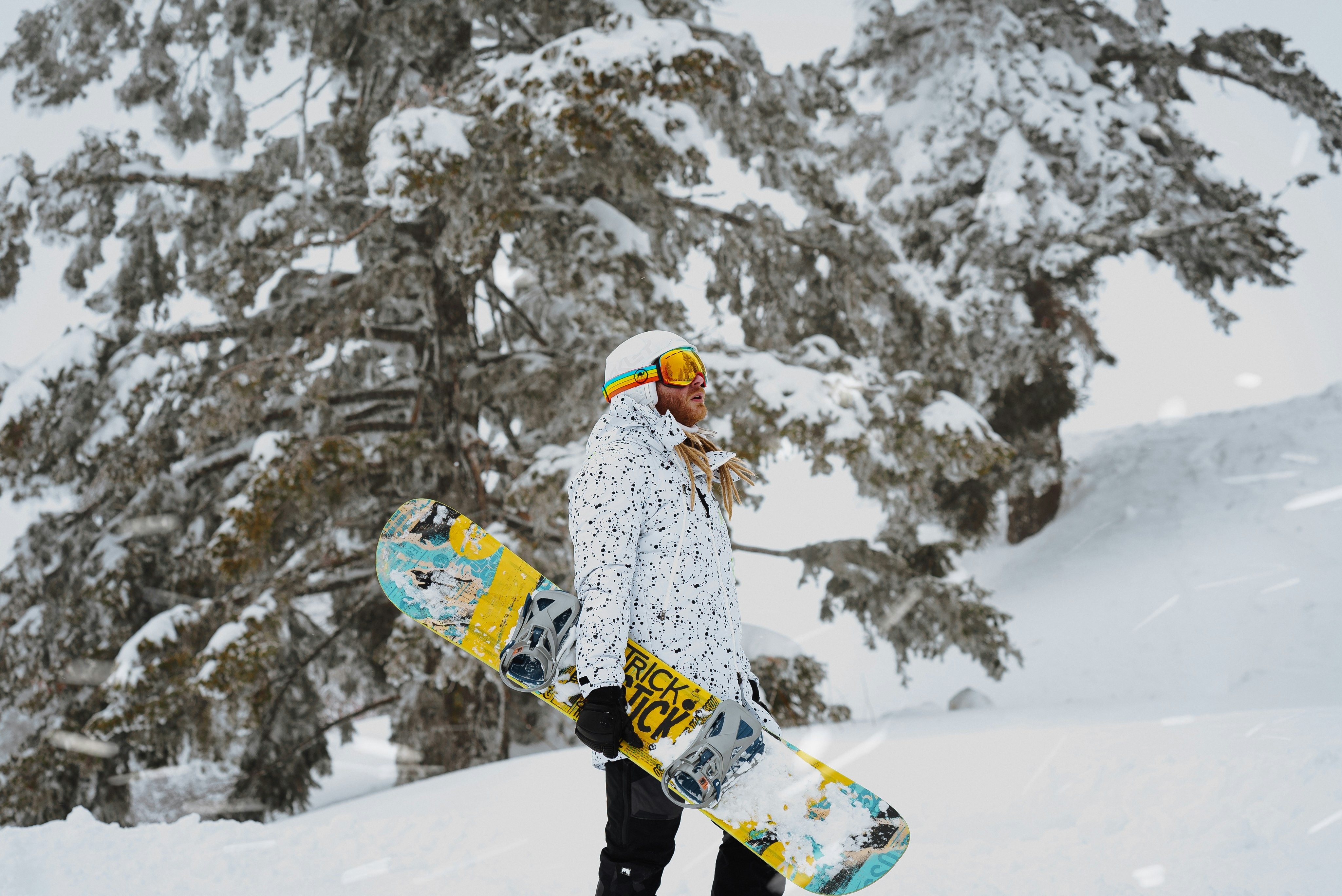 person in white and blue jacket and black pants riding on snowboard during daytime