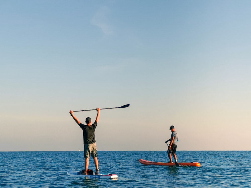 man and woman standing on blue surfboard during daytime