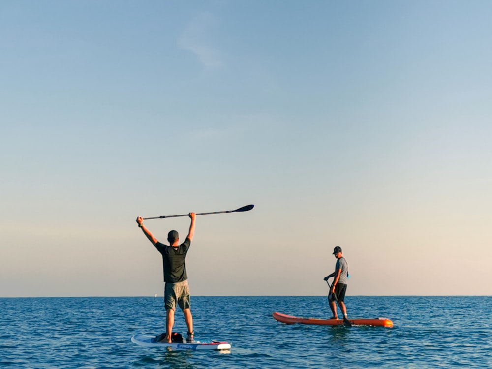 Mann und Frau stehen tagsüber auf blauem Surfbrett