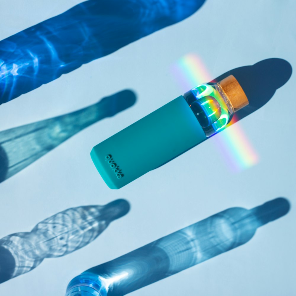 Linterna azul y negra junto a la botella de vidrio transparente