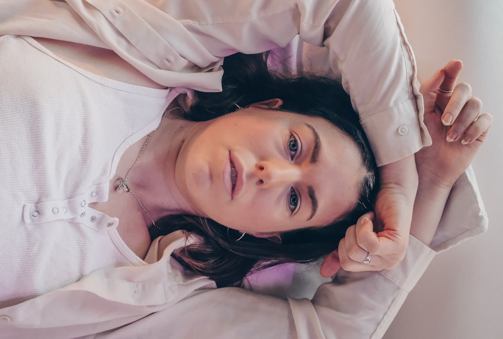 girl in white long sleeve shirt lying on bed