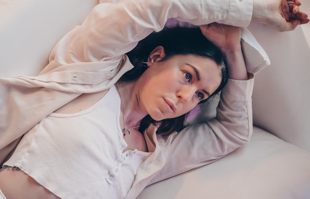 woman in white long sleeve shirt lying on bed