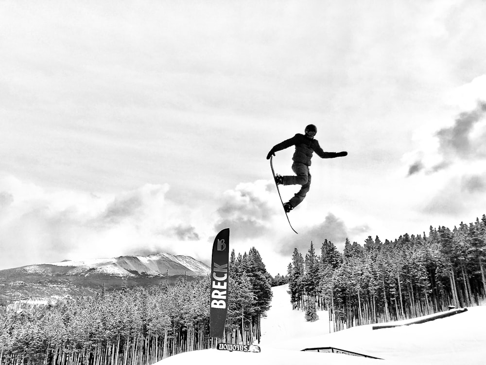 man in black jacket and pants riding on snowboard in snow covered field