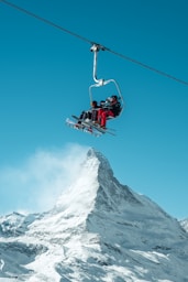 red and black cable car over snow covered mountain