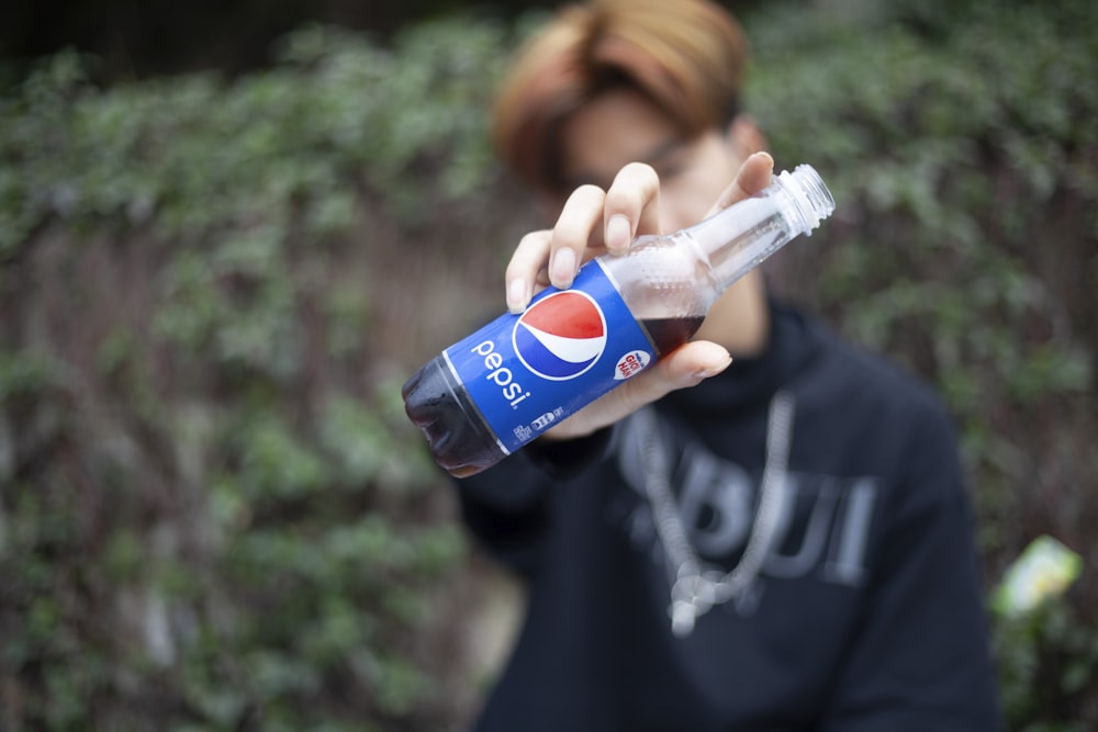 boy in black crew neck t-shirt holding pepsi can