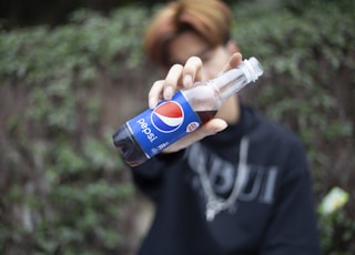 boy in black crew neck t-shirt holding pepsi can