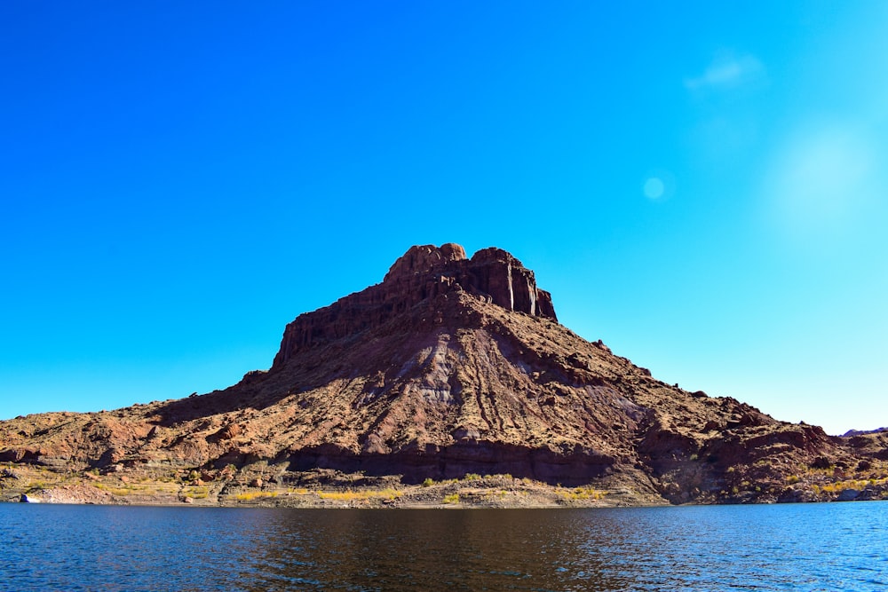 brown rocky mountain beside body of water during daytime