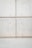 A concrete wall with a grid pattern is formed by the intersection of vertical and horizontal seams. The surface is smooth with visible small, round indentations evenly distributed across the panels. The lower section of the image shows a plain concrete floor.