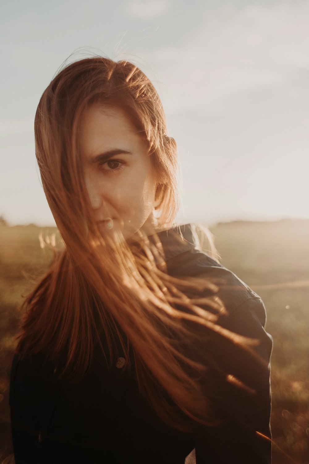 woman in black jacket standing on brown field during daytime