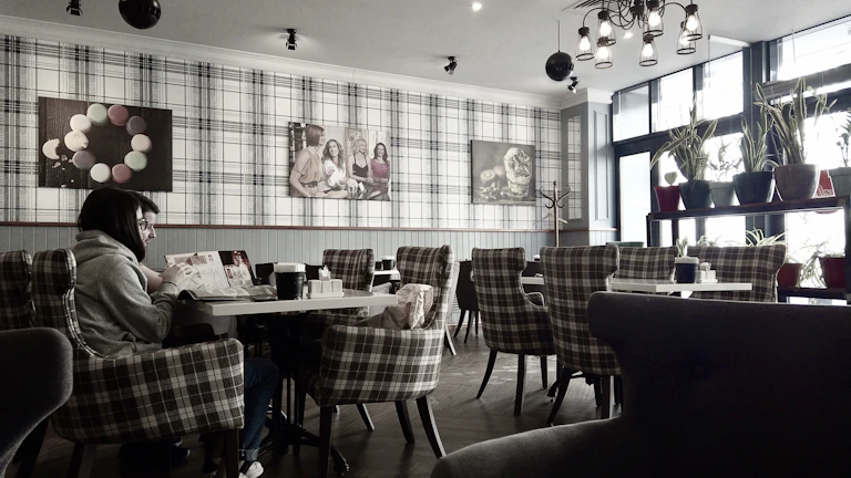 The quiet, upscale ambiance of Hiranandani Hillcrest cafe, with minimalist decor and a single patron reading.