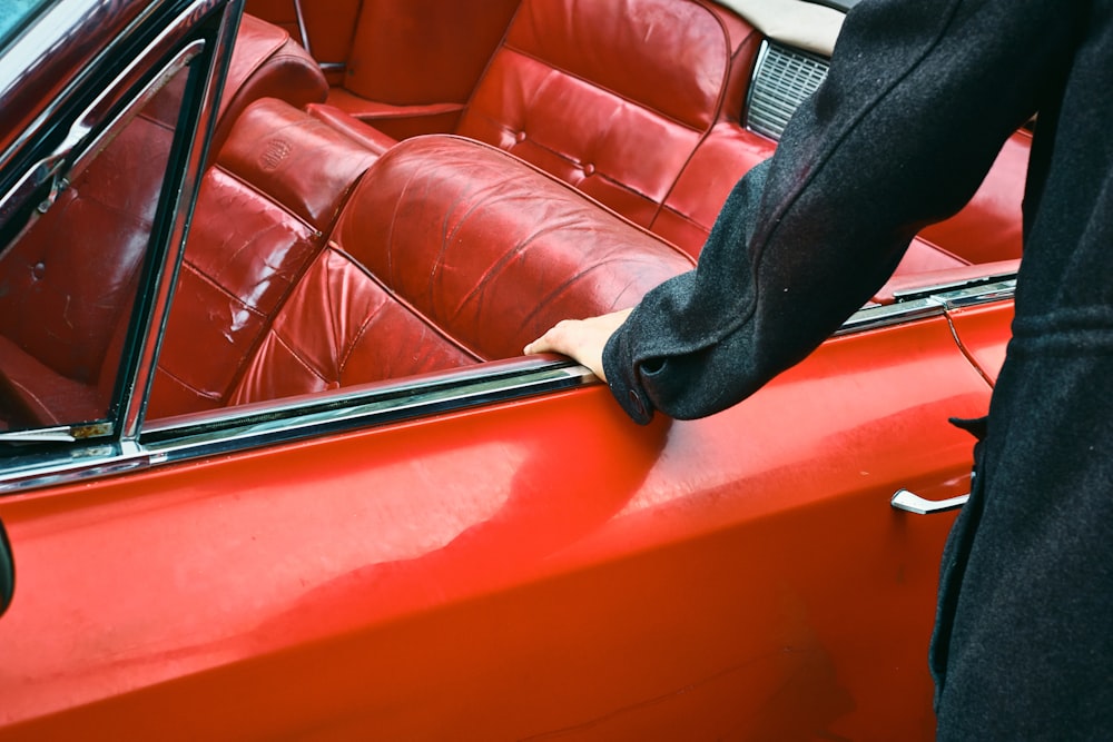 person in black pants sitting on red leather couch